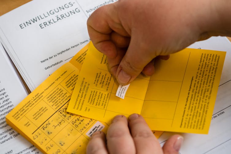 Hand applying sticker to vaccination certificate