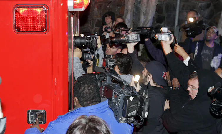 swarm of photographers around ambulance