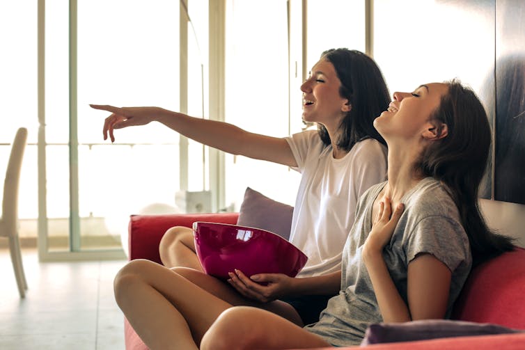 Image of two girls laughing in front of the TV.