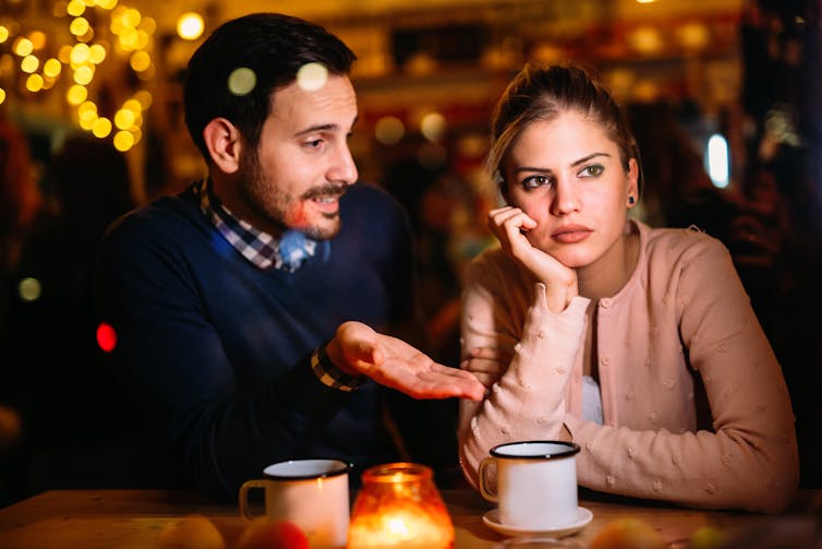 A man appears to be boring a woman in conversation in a bar