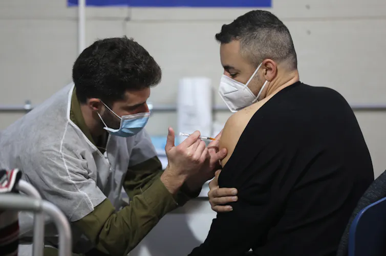 A man wearing a COVID mask getting vaccinated