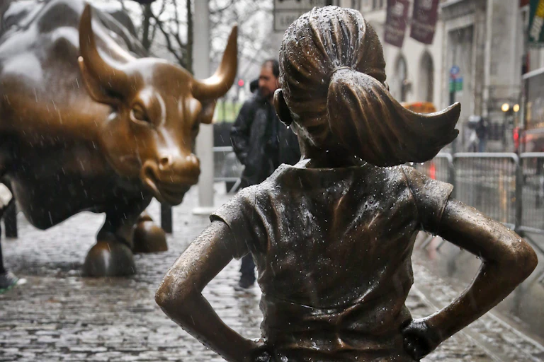 The Fearless Girl statue faces the Charging Bull statue.