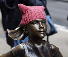 The Fearless Girl statue wearing a pink pussy hat.