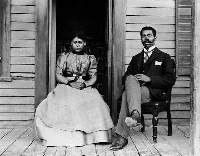 Betty and Willis Coles pose on a porch sitting in chairs.