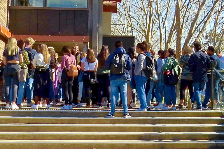 University students waiting on steps outside building