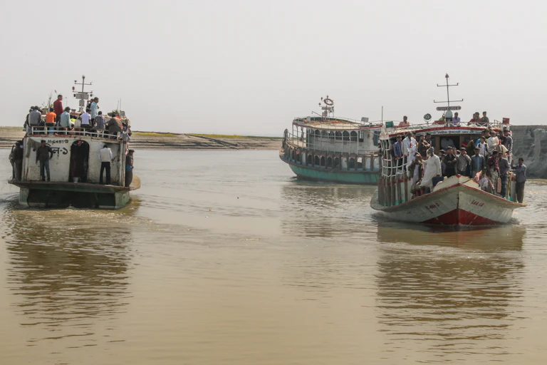 Three boats full of people on a river.