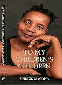 A woman with short dreadlocks leans her cheek against her hand as she looks into the camera with a slight smile.