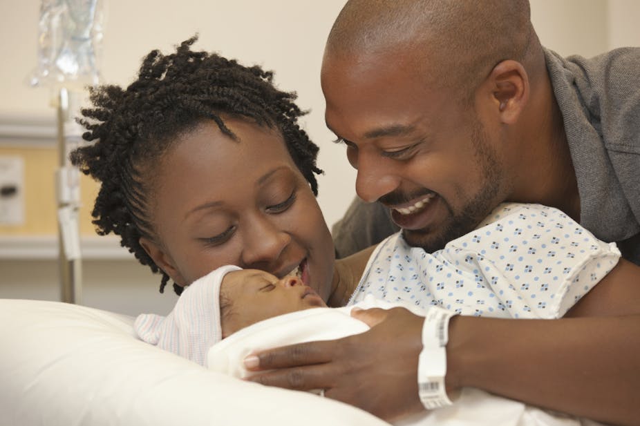 Black couple in hospital looking at newborn baby