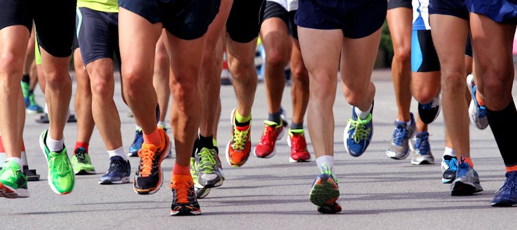 Many runners' legs and shoes running on tarmac