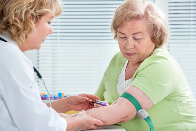Female doctor draws blood from an older woman's arm.