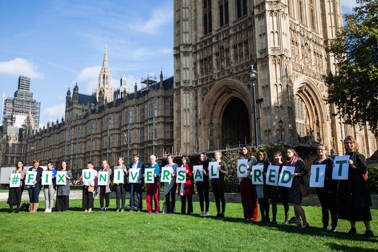 Protesters outside parliament hold up signs spelling 'FIX UNIVERSAL CREDIT'