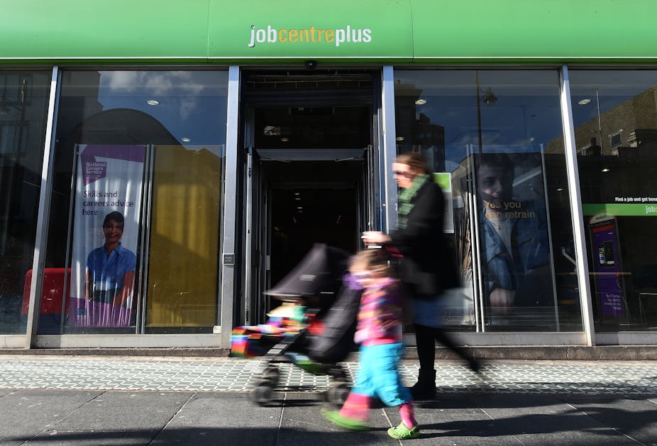 Woman pushes buggy past job centre with child next to her