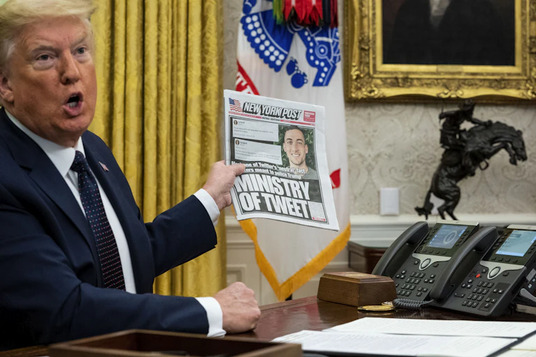 Donald Trump in the White House holds up a copy of the New York Post with a front page about his use of Twitter.