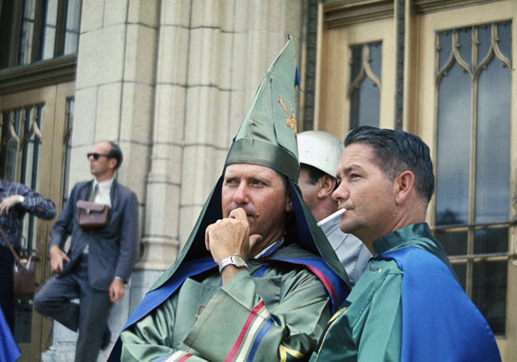 Two Ku Klux Klan leaders in uniform stand close together