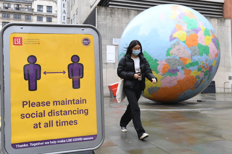 A woman walks past an upside globe on the streets of London