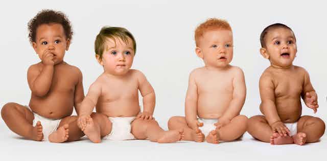 Babies sitting against a white background wearing nappies.