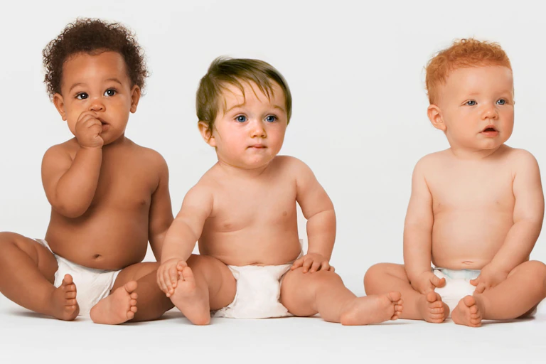 Babies sitting against a white background wearing nappies.