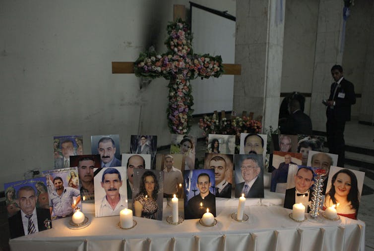 About two dozen photographs displayed on a table with lit candles.
