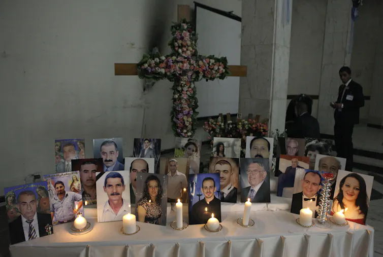 About two dozen photographs displayed on a table with lit candles.