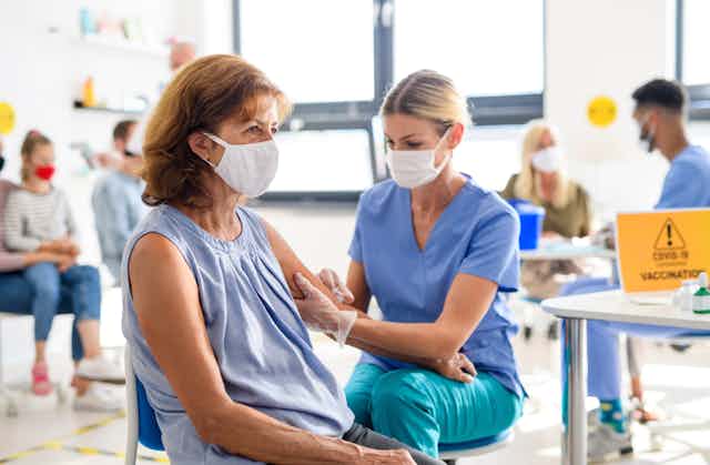Woman wearing mask getting COVID vaccine