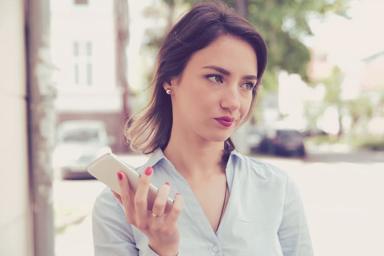 A woman looks disappointed while holding her phone.