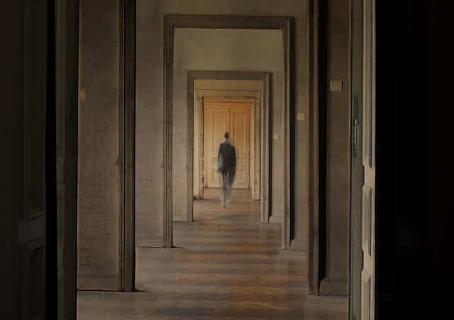 A person seen in the distance through several doorways.