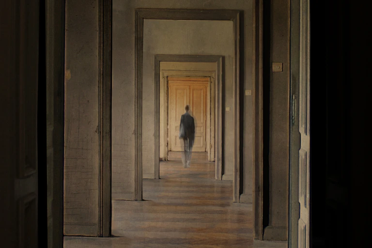 A person seen in the distance through several doorways.