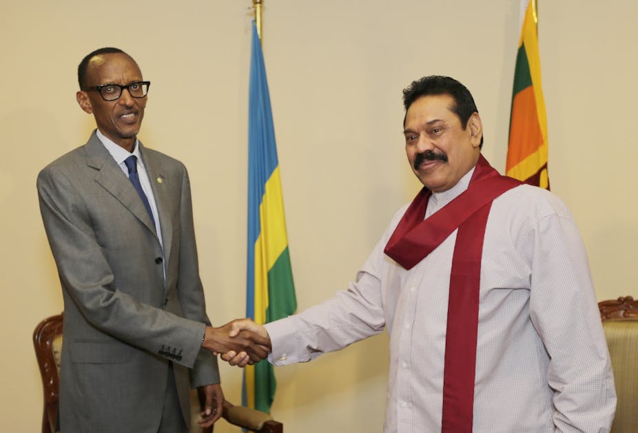 A black man in a suit shaking hands with a brown man in traditional Sri Lankan garb