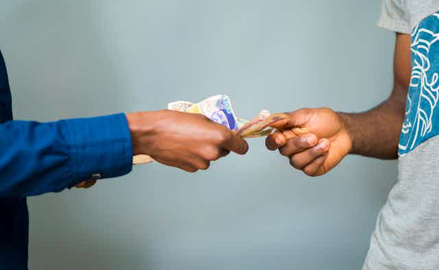 Two hands exchanging money.