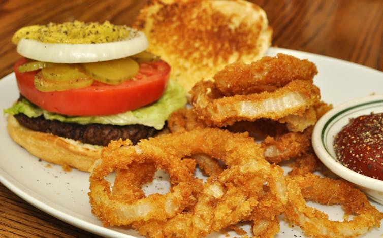 A hamburger and onion rings on a plate.