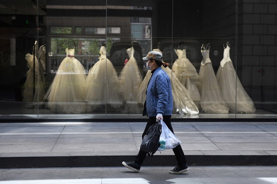 Une femme passe devant les robes de mariée exposées dans un magasin à Pékin, le 22 avril 2020.