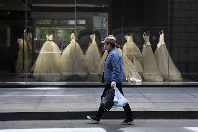 Une femme passe devant les robes de mariée exposées dans un magasin à Pékin, le 22 avril 2020.