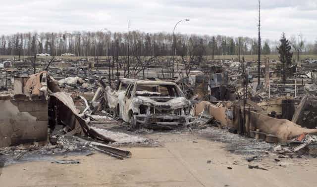 Burned trucks and cars surrounded by the remains of houses in a neighbourhood.