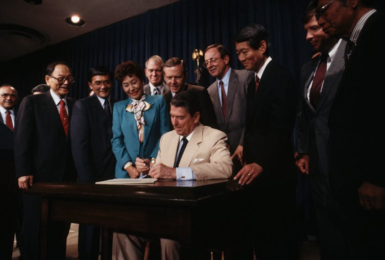 Congressmen surround President Ronald Reagan.