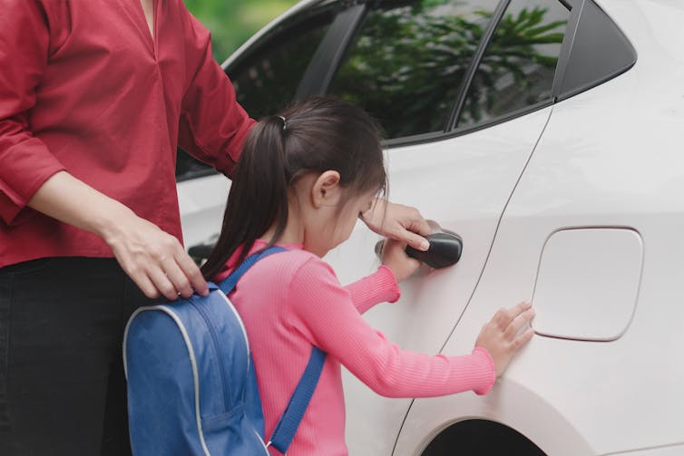 Mother opens car door for girl going home after school