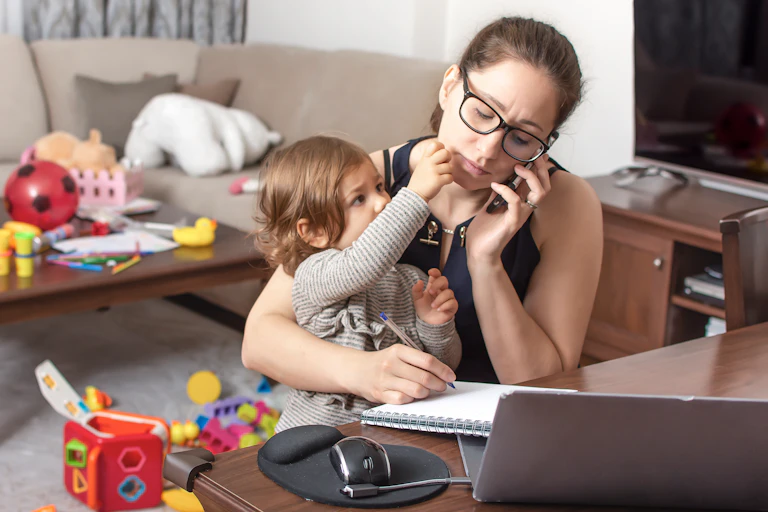 A woman working at home and caring for her child.