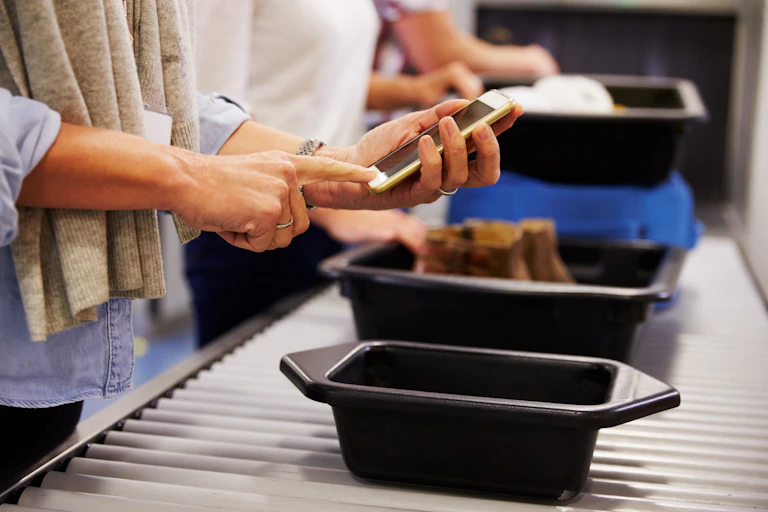 Person looks through phone at airport security.