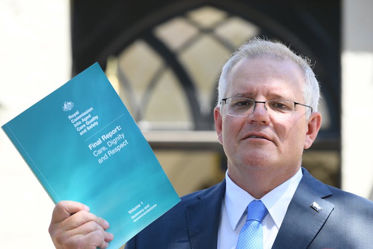 Prime Minister Scott Morrison holding a copy of the royal commission report.