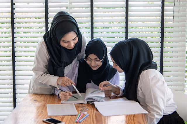 Islamic school girls looking at textbook