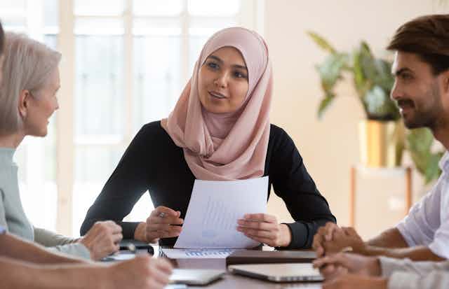 young muslim woman talking with diverse group of colleages