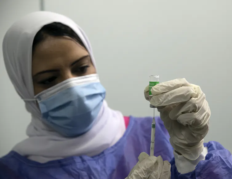 A health worker in Egypt loading a syringe with the Oxford/AstraZeneca vaccine