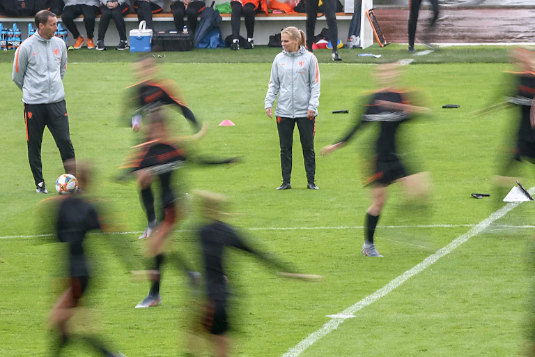 Football coaches with training footballers blurred out.