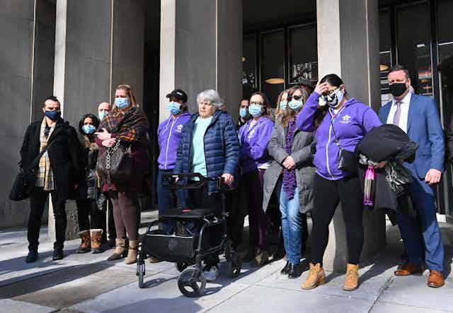 People stand in front of the courthouse wearing face masks