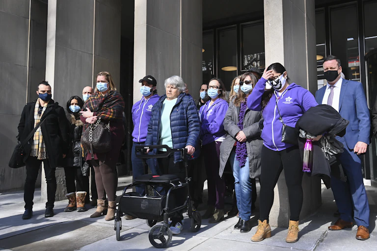 People stand in front of the courthouse wearing face masks