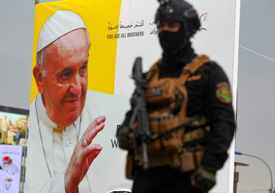Un militaire irakien devant une affiche représentant le pape François
