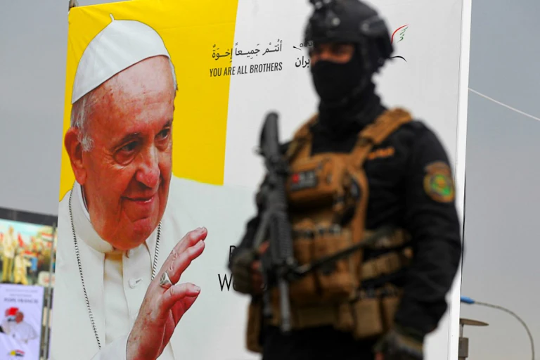 Un militaire irakien devant une affiche représentant le pape François