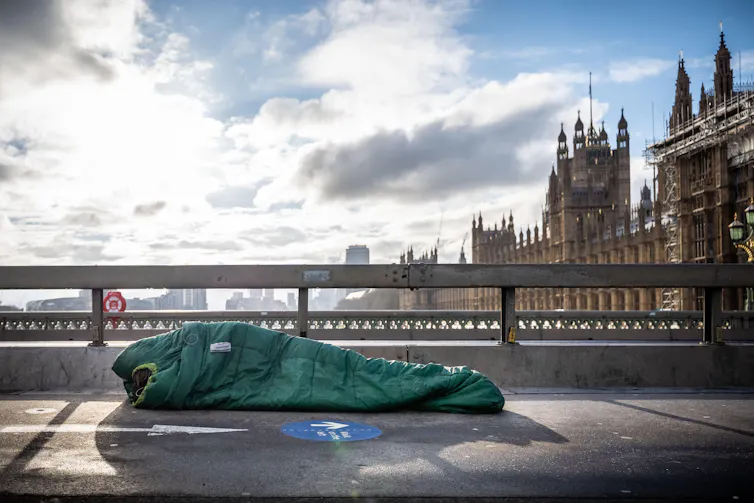 Rough sleeper in sleeping bag on Westminster bridge, London.