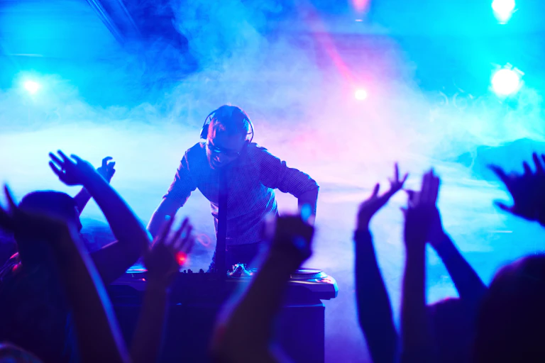 People dancing in a club as DJ mixes the music