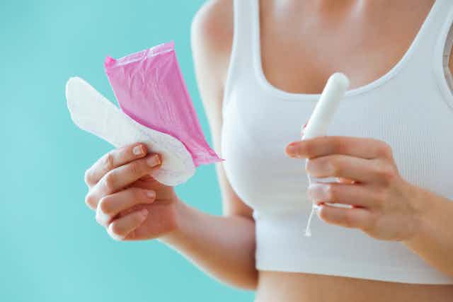Girl holding a pad and a tampon.