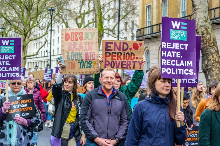 People hold signs reading 'end period poverty'.